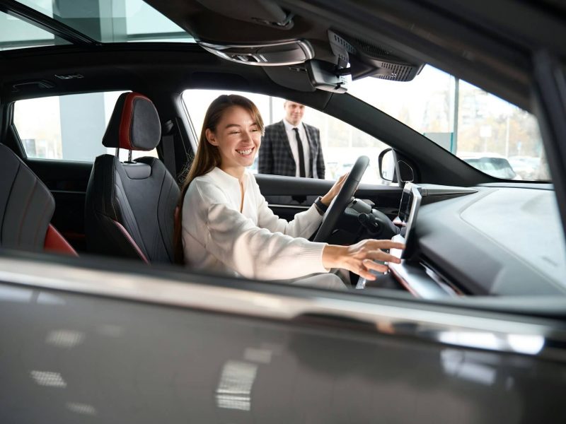woman-choosing-new-car-in-dealership-with-salesman-trying-on-new-automobile.jpg